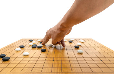 Hand playing board game of Go or Japanese chess board game, use black stones and white stones to create territory and capture opponent. Isolated image on white background.