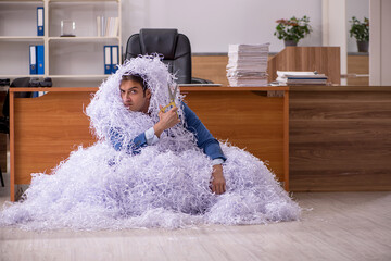 Young male employee and a lot of cut papers in the office