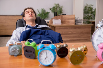Young male employee sleeping in the office in time management co