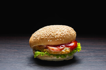 Closeup fresh burgers placed on a wooden plate in dark background.