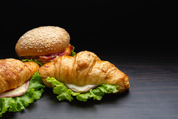 Closeup fresh burgers placed on a wooden plate in dark background.