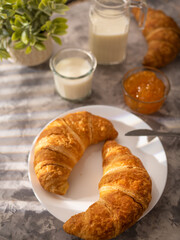 Morning breakfast with croissants, orange jam and milk. Morning light