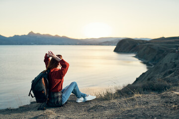 woman tourist with a backpack in the mountains at sunset near the sea top view