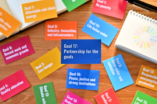 There is a card with the statement Goal 17:Partnership for the goals on table one of the goals of the SDGs and a symbol.