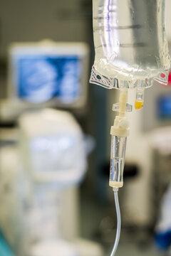 Intravenous fluid observation chamber - close up view in an operating theatre - background of surgical and xray monitors. 