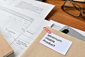 There is card with the word Minimun Viable Product on it with dummy paper of design of web systems.