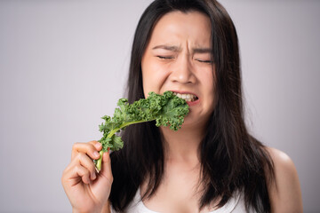 Asian woman trying to kale for diet isolated over white background.