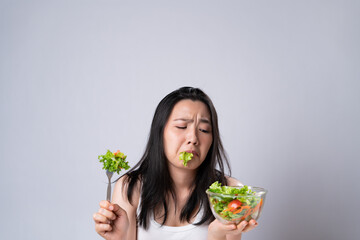 Asian woman trying to eat salad for diet isolated over white background.