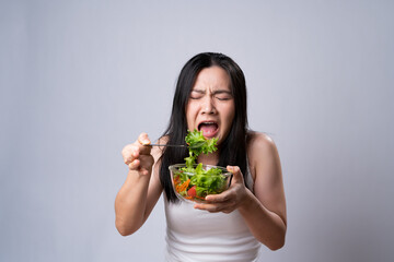 Asian woman trying to eat salad for diet isolated over white background.