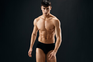 a man in dark shorts with a muscular body on a dark background bodybuilder