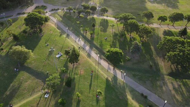 Aerial shot of one boy riding bicycle in green park at sunset