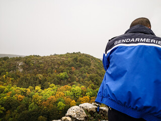 Un gendarme surveillant la montagne. Un policier surveille la forêt. Une patrouille de gendarmerie...