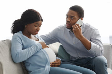Attentive black husband calling doctor while wife having labor pains © Prostock-studio