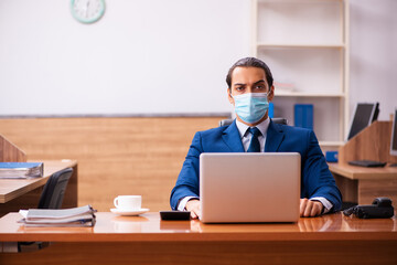 Young male employee working in the office wearing mask