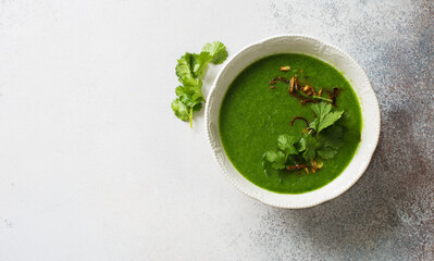 Bowl of broccoli, spinach, cilantro vegan soup on gray stone background. Flat lay. Copy space