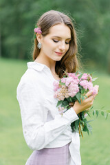 Young girl stand at park background with bouquet of  pink spireya flowers