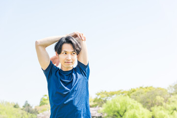 公園でランニング前にストレッチをする若い男性