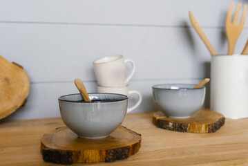 Fototapeta na wymiar Ceramic tureen with a wooden spoon on a sawn wooden stand in the kitchen in the Scandinavian style