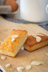 Gros plan sur des gâteaux financiers bien dorés sur une planche à découper parsemé d’amandes effilées