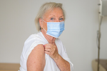 Senior lady lifting her sleeve to prove she has no ill effects from the Covid-19 vaccine