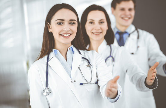 Doctors are standing as a team while offering their helping hands for shaking hand or saving people's life. Physicians are ready to help their patients. Medical help, insurance in health care, best