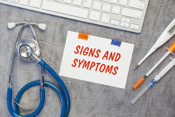 Paper with SIGNS AND SIMPTOMS on a table, stethoscope and pills