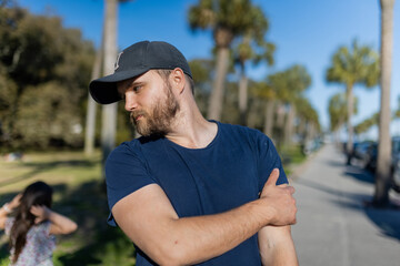 Obraz premium Bearded man standing with palm trees and blue sky as background