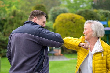 Grandmother greeting her grandson using her elbow during the Covid-19 pandemic