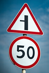 Road signs speed limit 50 km per hour. The road turns left. Close up shot