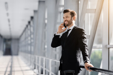 Handsome middle-aged businessman talking on phone in airport