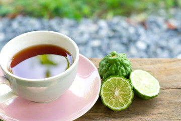 Bergamot tea or Earl Grey tea in white cup and fresh bergamot fruit with sliced on wooden table and blur background.