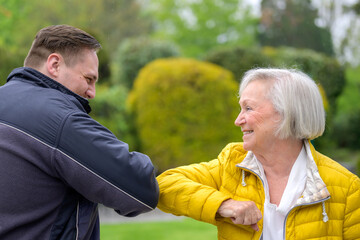 Grandmother greeting her grandson using her elbow during the Covid-19 pandemic