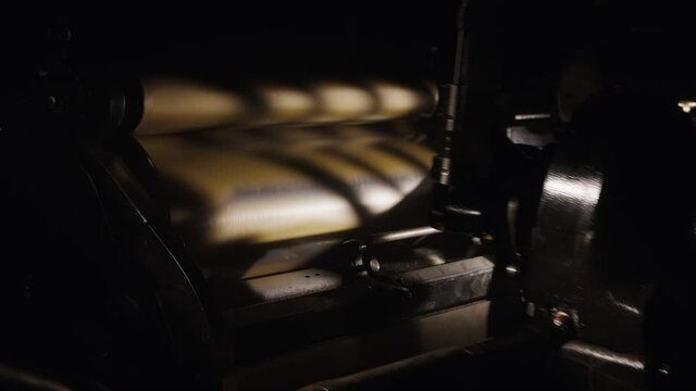 Old machinery working in a hazy, vintage workshop. Gears spinning, metal machines, historical printing studio. Industrial scene, antique, classic letterpress studio, making books, precision and art.