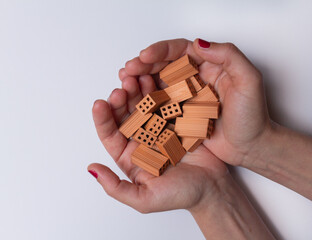 Two female hands with a lot of small toy bricks on a white background