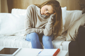 Obraz premium Tired upset woman worried about tiredness from work at home office and self isolation quarantine for COVID-19 Coronavirus. Mental health, anxiety depressed thinking young lady