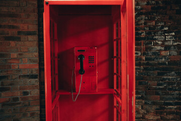 Old school red payphone inside vintage red telephone booth - obrazy, fototapety, plakaty