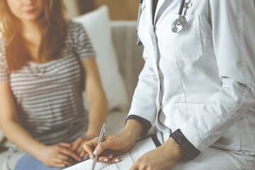 Close-up of woman-doctor and patient discussing current health examination while sitting indoors....