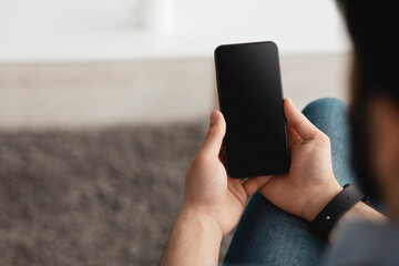 People and technology concept. Over the shoulder view of guy using smartphone with blank screen for mockup