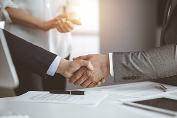 Business people shaking hands finishing contract signing in sunny office, close-up. Handshake and marketing