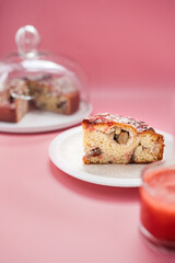 A piece of a rhubarb cake with strawberry marmalade on a pink background