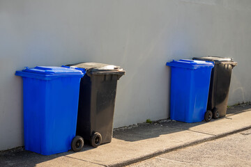 Blue and grey plastic wheelie bins out in a street ready for collection. Recycle industry concept....