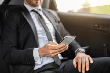 Cropped of manager sitting in car and using smartphone