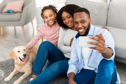 Young black family taking selfie with dog at home