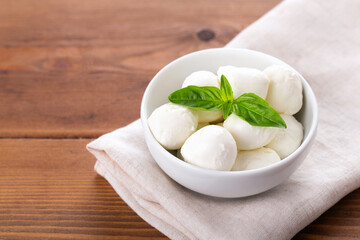 mozzarella balls with fresh basil on wooden background, horizontal, space for text