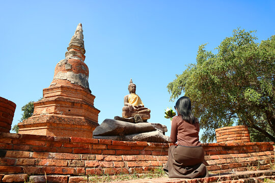 Woman praying in front of Buddha image at Wat Phra Ngam temple ruins in Ayutthaya, Thailand