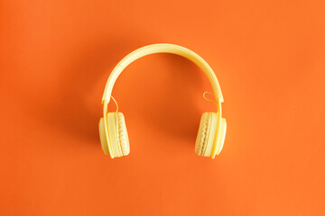 Top view of yellow headphones. Entertainment concept. On pastel orange background.