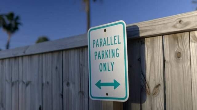 Parallel parking only sign on wooden fence with blue sky as background