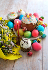 spring flowers, Easter cakes (orthodox kulich), candle, colorful eggs. Easter holiday scene. Festive composition on table. 
