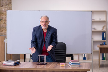 Old teacher physicist sitting in the classroom