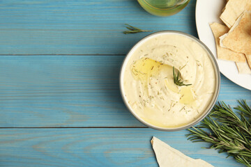 Delicious hummus with rosemary and pita chips on turquoise wooden table, flat lay. Space for text